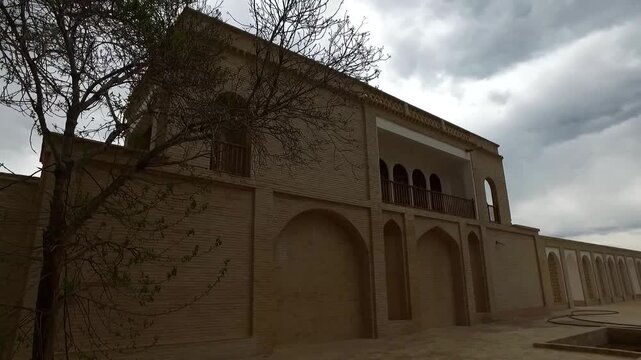  Exterior of an ancient mudbrick building with weathered walls and simple tower, showcasing traditional desert architecture, historical significance, and timeless beauty in a remote setting. 