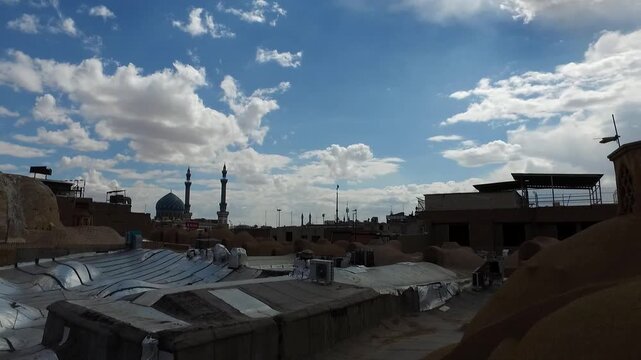  Wide view of traditional city rooftops and mud domes under a blue sky with white clouds. This footage captures the scenic landscape and ancient urban planning of a historical desert region. 