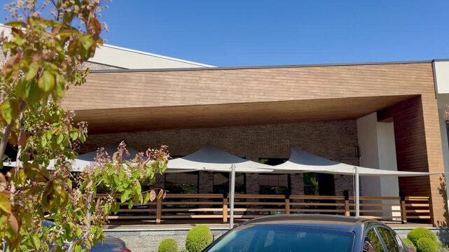 Modern Commercial Building with Wooden Facade, Terrace with Sun Sails and Blue Sky