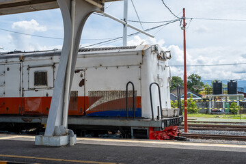Railway maintenance worker inspecting train engine at station platform, showcasing industrial activity and transportation infrastructure in daylight. © InveStock