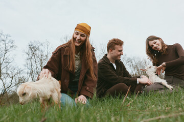 Fototapeta premium Goat kid lifestyle outdoor nature friends countryside happiness shown as a joyful group outdoors with a goat kid, smiling friends share time in a grassy field, a casual moment capturing bonding,