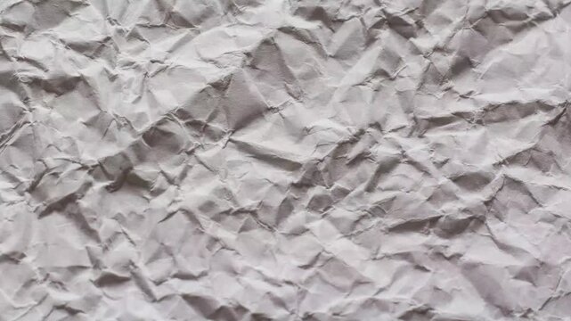 Closeup of a heavily crumpled white paper texture with deep shadows and creases animated background