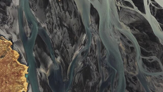 Drone view of braided rivers in Iceland, showing winding water channels across a glacial plain. Abstract natural patterns in a dramatic Arctic landscape.