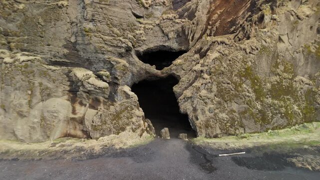 Drone view of cave formations at Hj&ouml;rleifsh&ouml;f&eth;i, known for its unique shape and volcanic surroundings. Dramatic landscape with black sand and rugged terrain. The Yoda Cave.