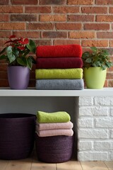 Obraz premium Stacked colorful towels with plants and baskets on shelves