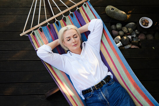 Mature woman relaxing in colorful hammock on backyard deck