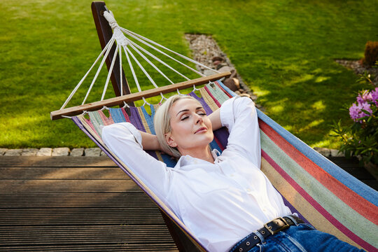 Mature woman relaxing in hammock in sunny backyard