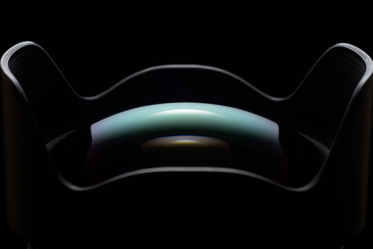Wide-angle camera lens with hood showing optics reflection on black background