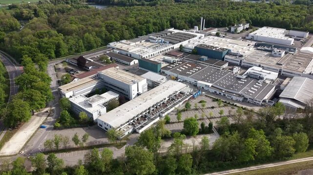 Drone lateral movement capturing a large industrial factory complex near a river, with visible logistics and infrastructure, representing manufacturing and industry.
