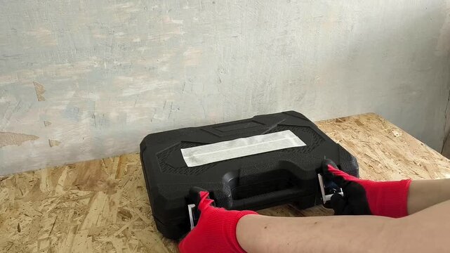 The hands of the repairman in gloves open a case with a ratchet, tools, screwdriver attachments. Repair. Hand Tool Set. Car repair shop, garage
