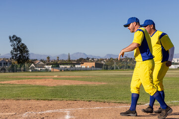 Obraz premium Senior mature male teammates walking baseline on baseball field in yellow-blue uniforms, copy space