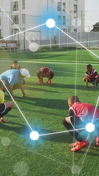 Vertical video: Coach demonstrating sports warmup, boys mirroring on turf, nodes linking squats
