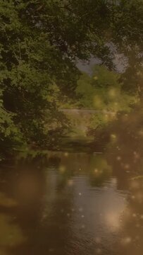 Vertical video: Sparks rising, cam panning right revealing river and arch bridge showing green bank