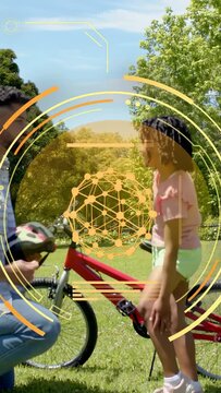 Vertical video: Kid nearing red bike dad fitting helmet buckling strap safely, amber rings overlay