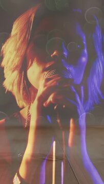 Vertical video: Music performer leaning into mic as camera rising, singing with bokeh on face