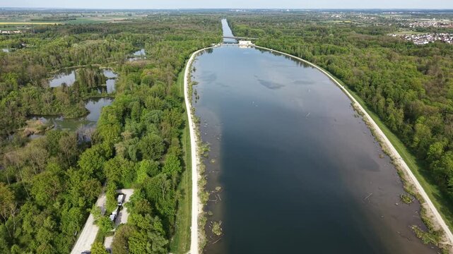 Drone forward shot showing a wide river section gradually narrowing after a dam, illustrating water flow and landscape change.