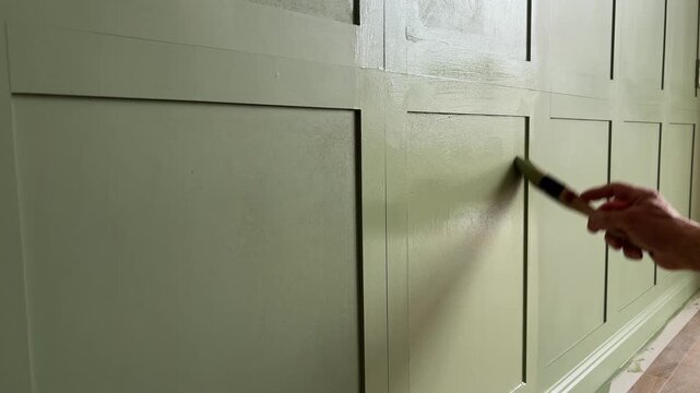 Painting wall mounted MDF panels with interior green paint in the bedroom. Medium Density Fiberboard. 
