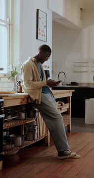 Typing, laughing and black man in kitchen, phone for online chatting and app for communication. Happy, mobile user and African person in home, tech for comedy and scroll for entertainment or smile
