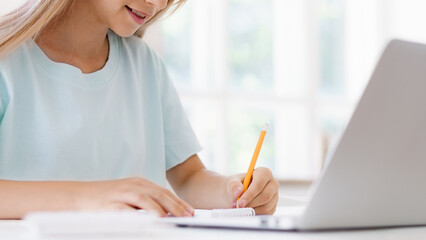Student writes notes while studying at home during daytime