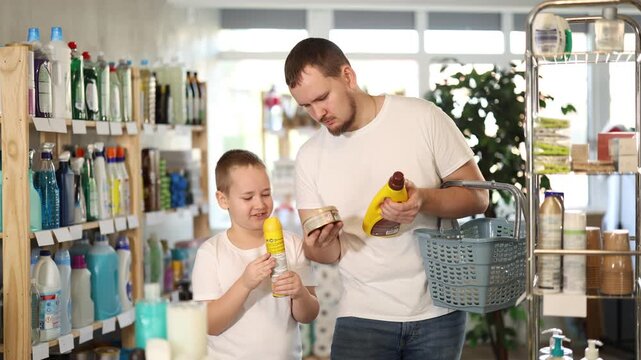 Young man with his son buyers choosing parquet and wood cleaner in household chemicals store