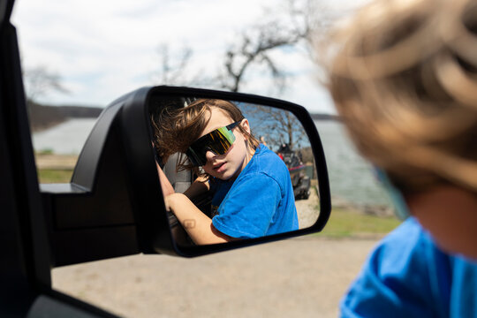 Reflection of a child wearing sunglasses in a vehicle side mirror