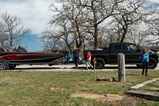 Family loading a fishing boat on trailer behind a black pickup truck