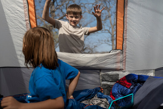 Two young boys playing and interacting through a mesh tent window