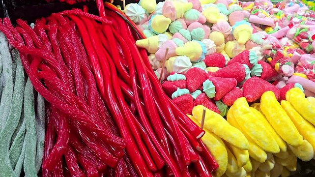 Close up shot of assorted gummy candy and jelly sweets covered with sugar, arranged on a market stand, showing bright colors, rich texture and tempting sugary treats in a lively fair atmosphere.