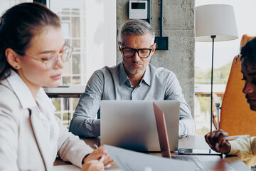 Fototapeta premium Experienced Leader Oversees Report Analysis While Fostering Teamwork And Composed Environment