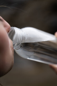 Close-up woman drinking water from bottle in soft daylight, wellness and hydration.