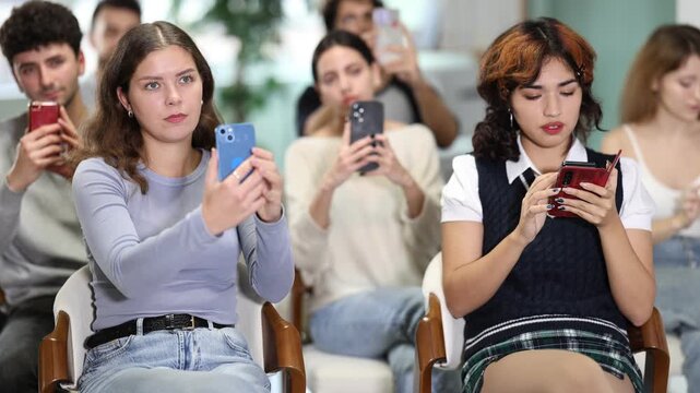Students take pictures of screen information. Young people are listening to lecture in auditorium. Personal growth courses, group psychological interaction, practical classes in psychology