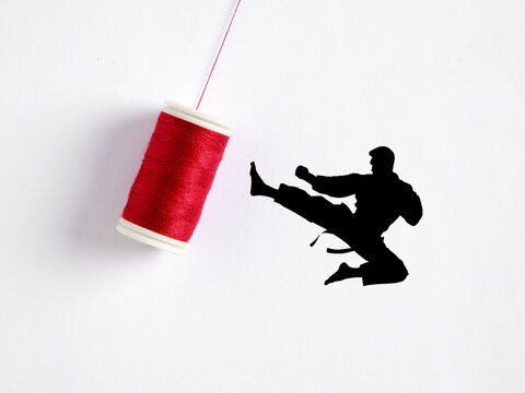 Karate fighter kicking red sewing thread spool hanging from a string