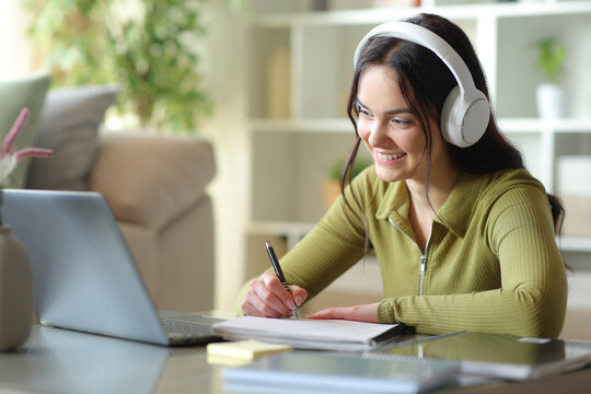 Happy teenage student e-learning and taking notes