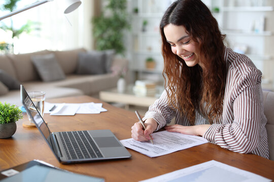 Happy young teleworker filling form working at home