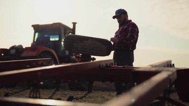 Agricultural machinery technician repairing wheel portrait in farmland in summer . Farming and agriculture, farmer working alone in field, Service and repair of equipment for harvesting and soiling