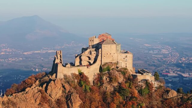 Aerial: sunset view of Saint Michael's Abbey in Sant'Ambrogio di Torino, Piedmont, Italy, orbit drone shot
