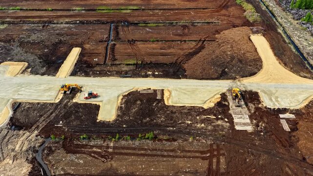 A drone glides past heavy machinery and excavators preparing land for new roads.