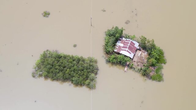 Rural village home isolated by monsoon flood water in Sylhet, Bangladesh - top down ascending shot.