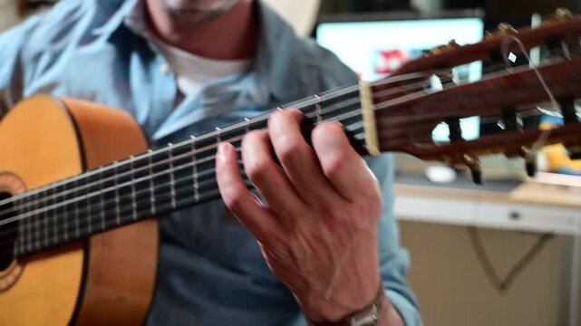 Anonymous musician attentively practicing classical guitar chords at home