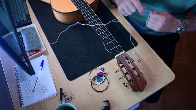 Musician changing and restringing a classical guitar at his desk
