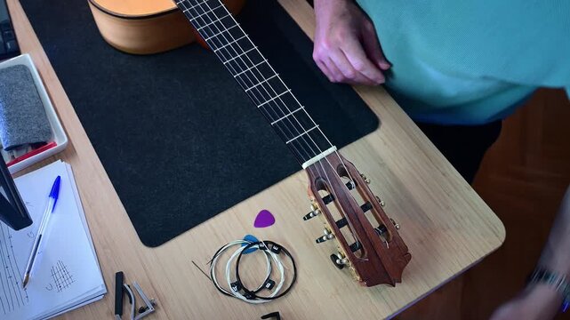 Man changing the strings of his classical guitar