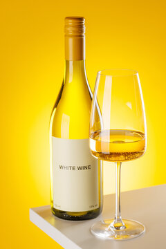 White wine bottle and glass on yellow background elegant drink setup