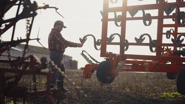 Rural life and farming, agronomist reading instruction for tractor in smartphone . Phone addiction, mobile gadget overuse, modern technology for agribusiness and agriculture, villager in farmland