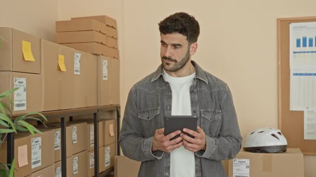 Man holding tablet checks stacked parcels in a small business stockroom inside a building; small business pride.