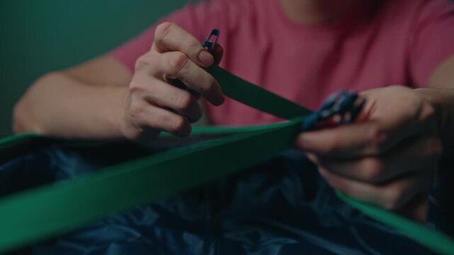 Cropped shot of man organizing baggage for journey. Close-up hands fastening elastic retaining straps inside suitcase to secure belongings for long vacation or trip. Concept of travel organization.