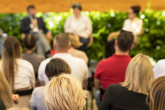 Outdoor business conference where a professional audience follows a presentation in a green garden setting, as part of a sustainably organized corporate event

