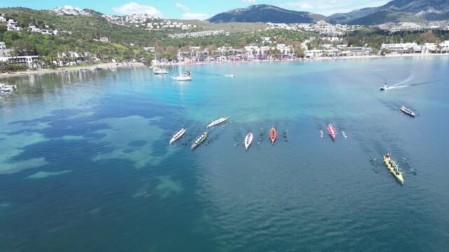 Aerial View of Professional Rowing Teams Competing in a Regatta near Scenic Coastal Town with Mountains. High quality 4k footage