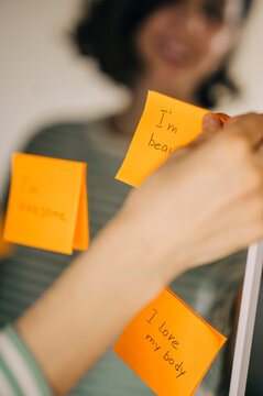 Smiling reflection behind positive affirmation notes on a mirror