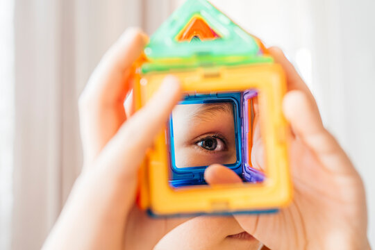 Eye looking through colorful constructor toy showing curiosity