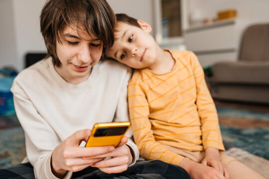 Brothers sitting together indoors looking at a smartphone
